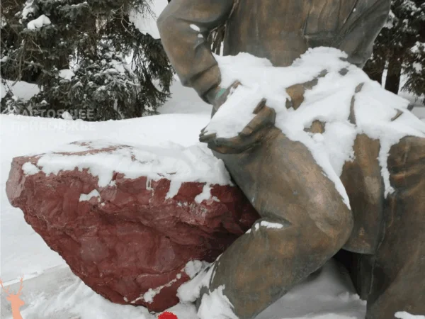 Полицейские в штатском дежурят у памятника, где лежат цветы в честь Навального